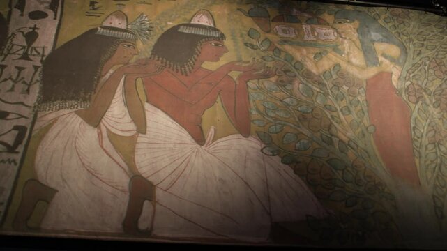 An ancient Egyptian fresco depicts two women in traditional attire making offerings to a deity. The artwork showcases detailed hieroglyphs and symbolic imagery, representing religious devotion.