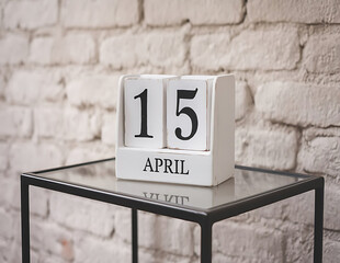 White block wooden calendar present date 15 april with candle and clook