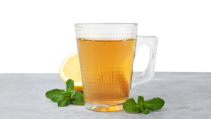 Aromatic mint tea in glass cup, fresh leaves and lemon on light gray table against white background