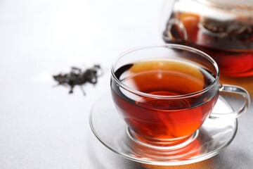 Aromatic black tea in cup on light table, closeup. Space for text