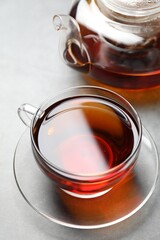 Aromatic black tea in cup and teapot on light table, closeup