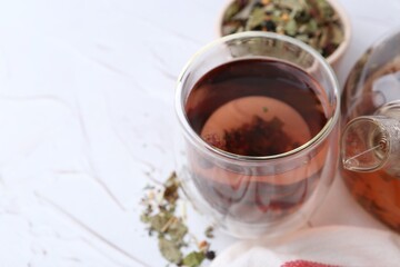 Delicious herbal tea and dry leaves on white table, closeup. Space for text