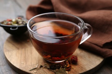 Delicious herbal tea and dry leaves on wooden table, closeup