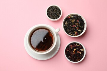 Aromatic tea and dried leaves on light pink background, flat lay