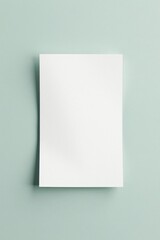 Fototapeta premium A Blank Square Sheet of Paper Resting on a Pale Green Surface, Ideal for Note-Taking, Messaging, or Design Mockups
