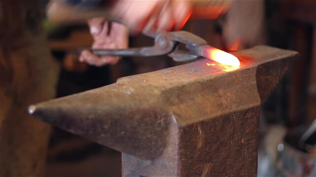 Blacksmith at Work, Close-up of Man Hitting a Red-hot Iron with a Hammer on the Anvil. Blacksmith Forging Red-hot Metal Bar in Smithy