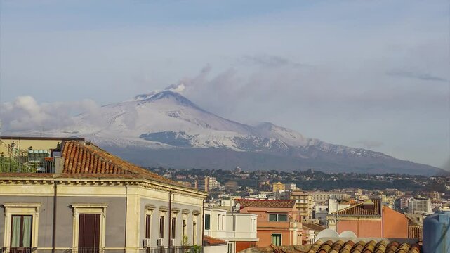 Time Lapse dell'eruzione del vulcano Etna innevato, del 13 febbraio 2025, con edifici e tetti della citt&agrave; di Catania in primo piano