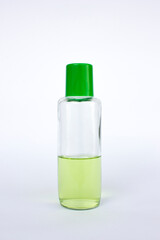 A transparent bottle with a green cap. It contains a green-colored liquid, a serum for health, isolated on white.
