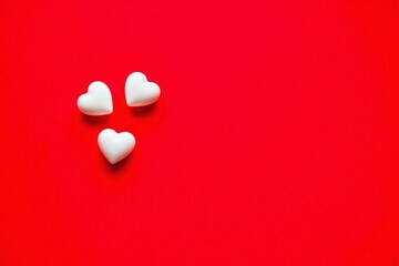 Two small white heart shaped objects bright red background