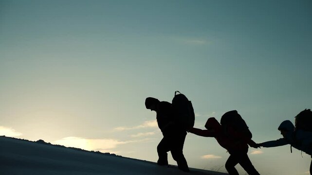 silhouette people climbers going forward mountain sunset. concept climbers with backpacks. teamwork. family trip mountains with backpacks winter sunset. campaign young successful winners. help hand