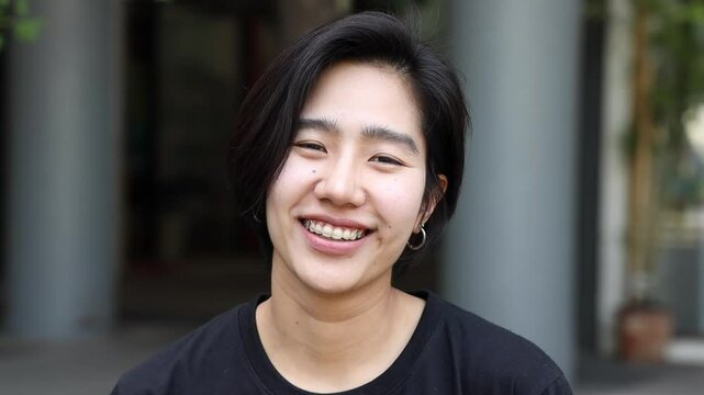 Happy friendly asian non-binary LGBT or QQIAA person smiling to camera