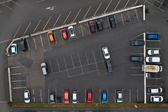 Des voitures sur un parking goudronn&eacute; en ville avec des places de libres