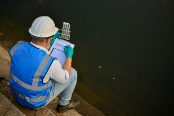 An expert ecologist is taking water samples back to a science lab to test aquatic life to examine...