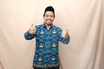 Handsome Indonesian government worker man wearing batik korpri uniform smiling and giving thumb up...