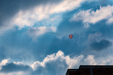kite flying in blue sky with rain clouds over building under construction
