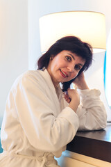 Woman hotel room combing hair sitting at table in front of mirror.