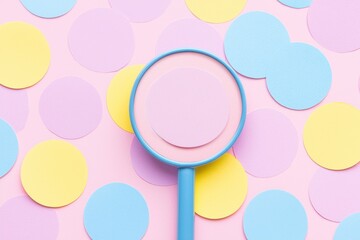 A vibrant top view of colorful circles with a magnifying glass highlighting a pink circle, creating a playful and cheerful atmosphere.