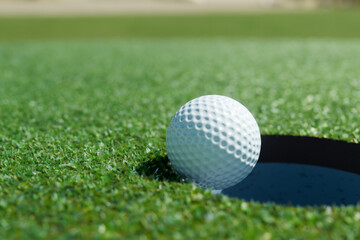 ゴルフボールがカップへ向かってグリーン上を転がってゆくイメージ
