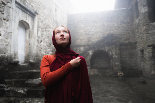 Low-angle shot of a young woman crossing herself and looking up to the sky. A devout white girl crosses oneself in church. Faith, Religion, Spirituality.