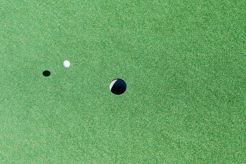 ゴルフボールがカップへ向かってグリーン上を転がってゆくイメージ
