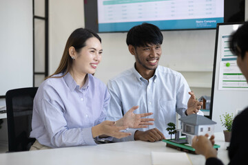 Three people are sitting at a table in a room with a whiteboard behind them. They are discussing something important
