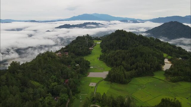 Aerial view of a drone flying over the misty forested mountains of Toraja, Indonesia. Foggy landscapes and green forests create a peaceful, mystical atmosphere in nature