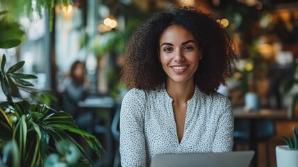 Businesswoman in a hybrid office space with an open laptop, collaborating with remote colleagues via video call in a bright, modern office.