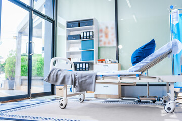 An empty medical bed sits in a glass hospital room, bathed in daylight. Equipped with adjustable features, it awaits the next patient, essential medical equipment for emergency and critical care.