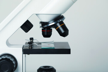 Science. Microscope with glass slide on light grey background, closeup. Space for text