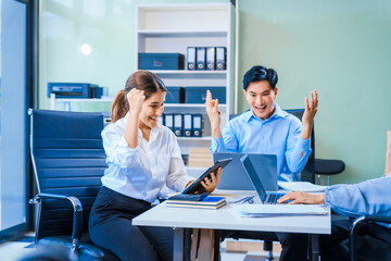 Middle-aged Asian man and Muslim woman in hijab sit across from each other in business meeting. They review report documents, discussing strategies and making decisions, successful, professional.