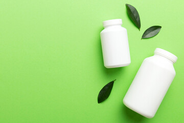 supplement pills with medicine bottle health care and medical top view. Vitamin tablets. Top view mockup bottle for pills and vitamins with green leaves, natural organic bio supplement, copy space
