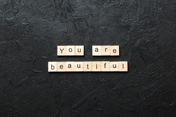 You are beautiful word written on wood block. You are beautiful text on cement table for your...