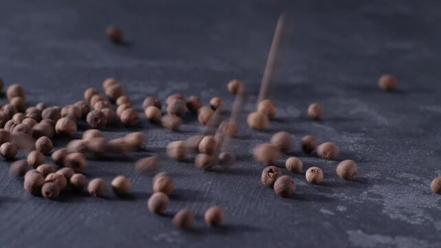 allspice or Jamaican pepper are poured into a black stone table.
