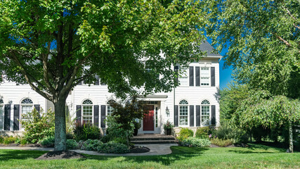 Fragment of a two-story modern house with brick trim. The house has traditional architectural elements such as gable roofs and decorative siding.