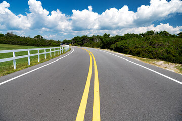 Yellow dividing strips on the road under a blue cloudy sky outside the city.