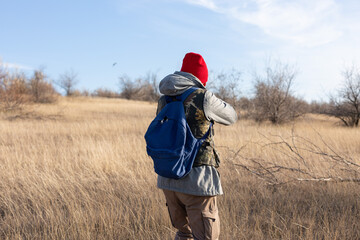 Mature hunter man holding a shotgun and walking through a field