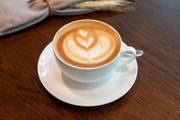 A hot latte with beautiful foam art sits alongside an English breakfast on a rustic wooden table, ideal for showcasing the comfort and charm of cafes and morning dining.