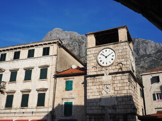 Historic clock tower in the Old Town of Kotor, Montenegro, with stone buildings, green shutters,...