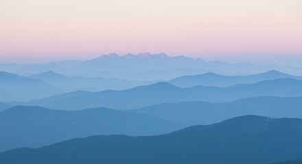Fototapeta premium Layered Blue Mountain Ranges at Dawn with Soft Hues and Mist