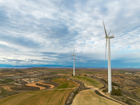 Aerial view of a wind turbine in Zaragoza, Spain, overlooking a patchwork of cultivated land. The renewable energy source stands prominently within the agricultural environment.