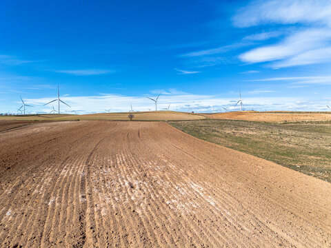 Aerial view of vast agricultural fields in Zaragoza, Spain, with rolling landscapes under a bright blue sky. The rich textures of the farmland create a striking natural pattern.