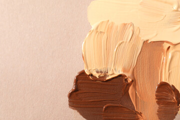 Samples of different foundations on beige background, closeup. Space for text