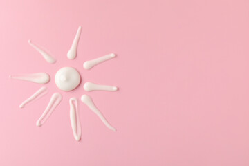 Sun shape made of cream on pink background, top view and space for text. Samples of cosmetic product