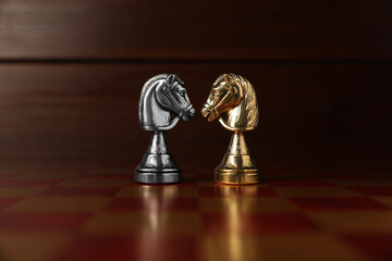 Golden and silver chess knights in middle of chessboard. Competition concept