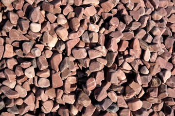 Natural pink gravel scattered on the ground in a sunny area