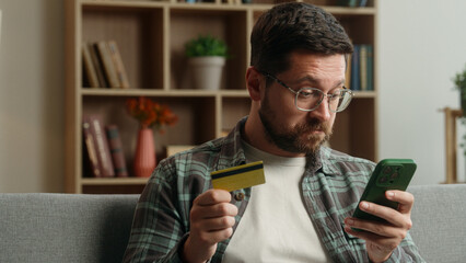 Confused puzzled angry Caucasian man male guy buying shopping online mobile phone smartphone buying...