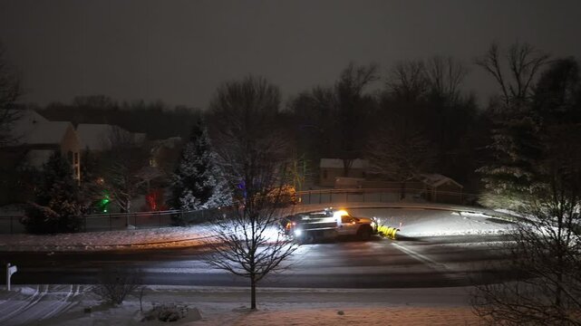 A snowplow truck plowing snow in a residential community at night in Garnet Valley, suburb of Philadelphia, Pennsylvania