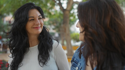 Fototapeta premium Two women enjoying their time outdoors in an urban park setting, showcasing friendship and happiness amidst the natural scenery.