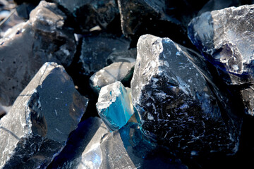 Unique blue crystal nestled among dark mineral rocks outdoors