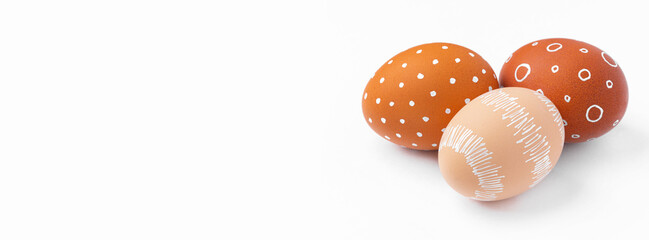 Natural brown Easter eggs with white minimalist patterns isolated on a white background